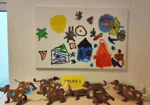 Prace dzieci - na szafce stoją psy (wypychanki) na ścianie wisi obraz namalowany przez uczestników gry ulicznej "Włókiennicza nas zachwyca".