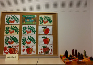 Prace dzieci - obrazki jarzębiny wyklejane plasteliną, papierowe jabłka pomalowane farbami oraz pomalowane, przyklejone do styropianu szyszki
