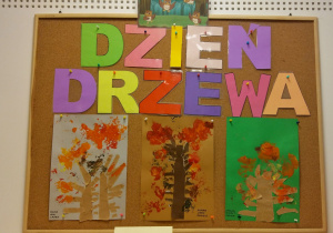 Prace dzieci - wykonane w grupach prace: wydarty z brązowego papieru i przyklejony do kartki pień drzewa wraz z gałęziami oraz ślady odciśniętych, pomalowanych farbą liści. Duży napis: dzień drzewa.