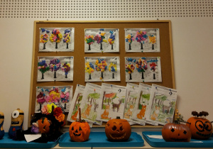 Tablica z pracami dzieci: szablony drzew wyklejone kolorową bibułą oraz jesienne karty pracy.