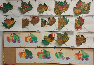 Tablica z pracami dzieci. Na górze znajdują się ususzone liście pomalowane farbami. Na dole znjadują się prace przedstawiające owoce wyklejone kolorową plastliną.