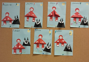 Tablica z pracami dzieci. Postaci Czerwonego Kapturka oraz wilka wykonane z figur geometrycznych.